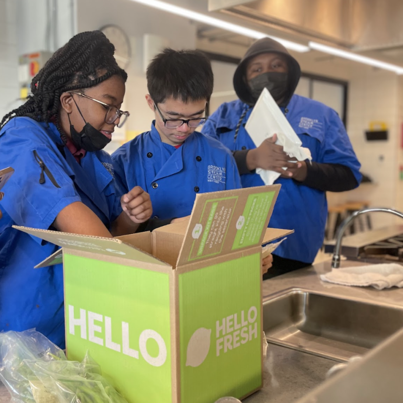 Two team members pack HelloFresh donation boxes to bring meals to those in need